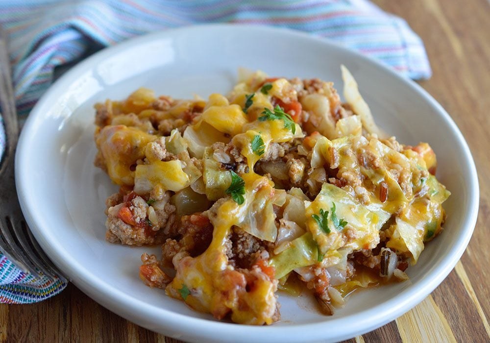 Stuffed cabbage casserole with ground turkey, rice and melted cheddar on a white plate
