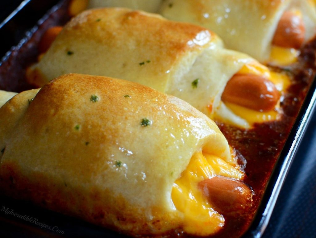 Chili cheese dogs wrapped in dough baked in a pan