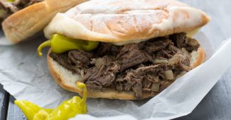 Crockpot Italian beef sandwiches on hoagie rolls with melted cheese and pepperoncini