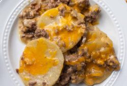 Crockpot hamburger potato casserole with melted cheddar on a white plate