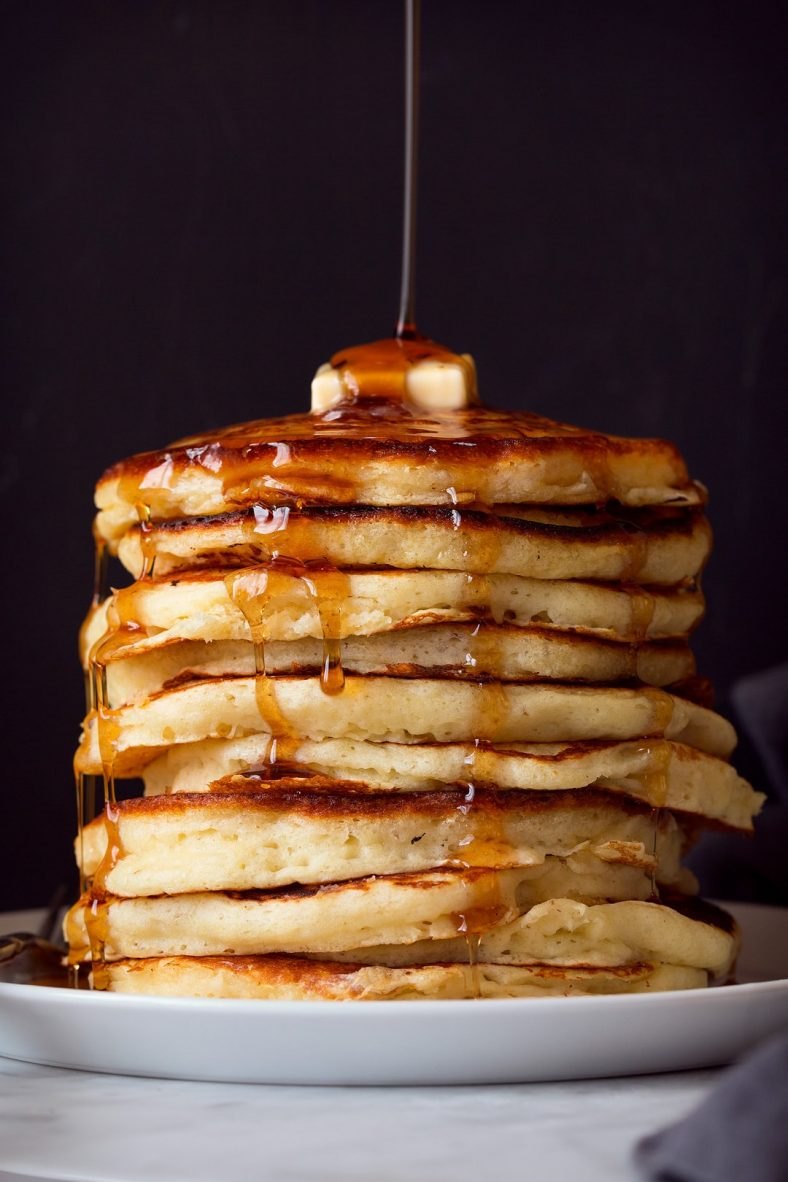 Tall stack of buttermilk pancakes with syrup
