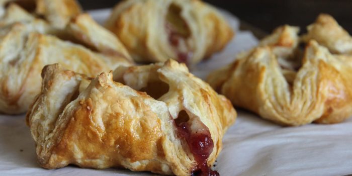 Golden puff pastry turkey cranberry brie pockets with cranberry sauce oozing out