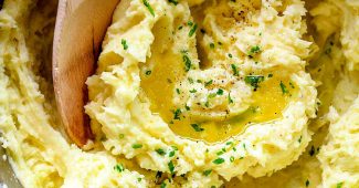 Creamy mashed potatoes in a pot with melted butter and chives