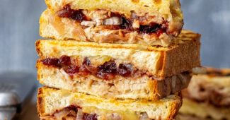 Grilled turkey cranberry panini halves stacked on a wooden board