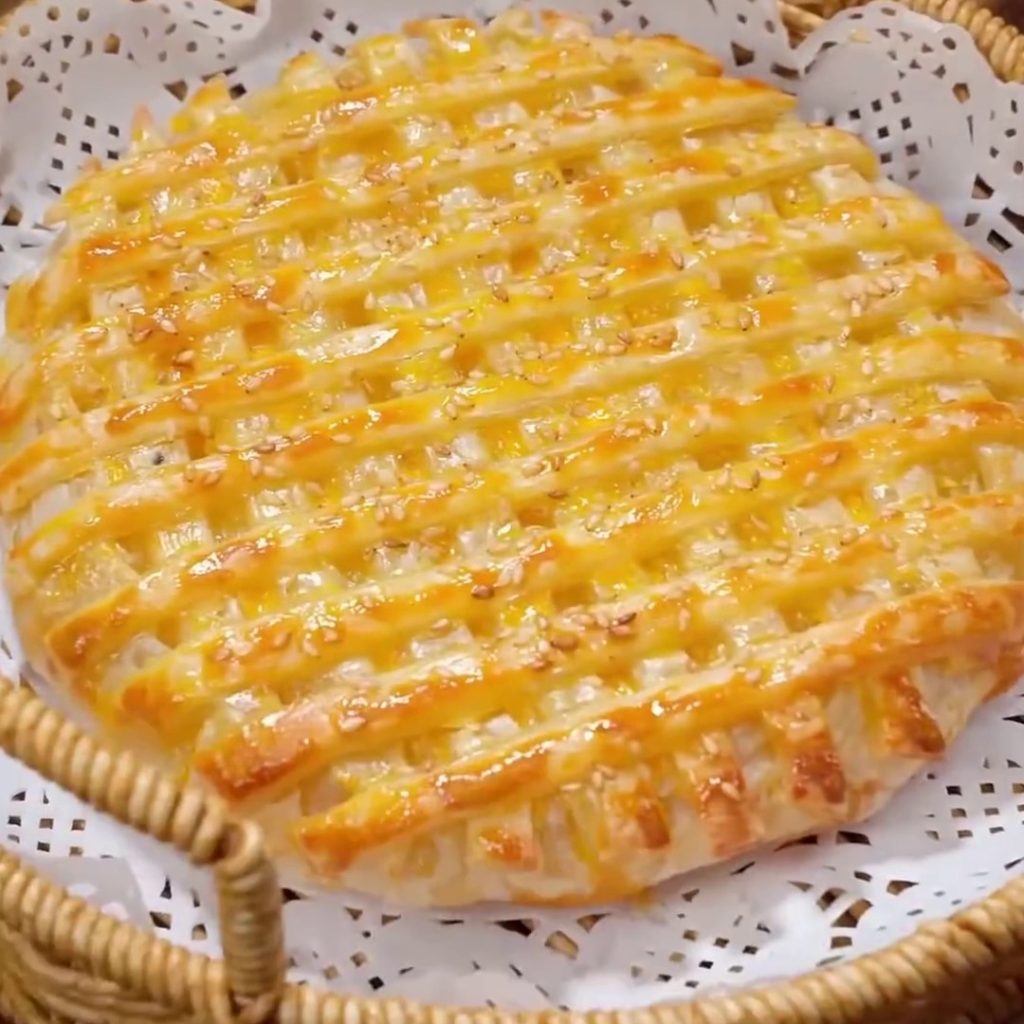 Golden air fryer pineapple pie with a lattice top and sesame seeds in a wicker basket