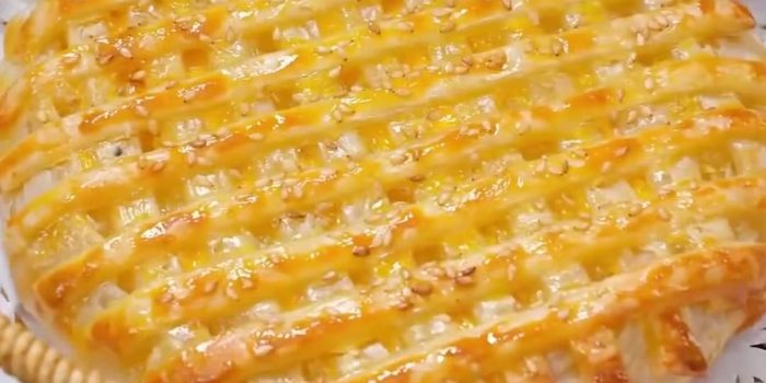 Golden air fryer pineapple pie with a lattice top and sesame seeds in a wicker basket