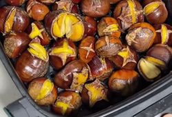 Roasted chestnuts with split shells in an air fryer basket