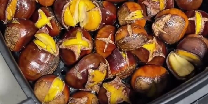 Roasted chestnuts with split shells in an air fryer basket