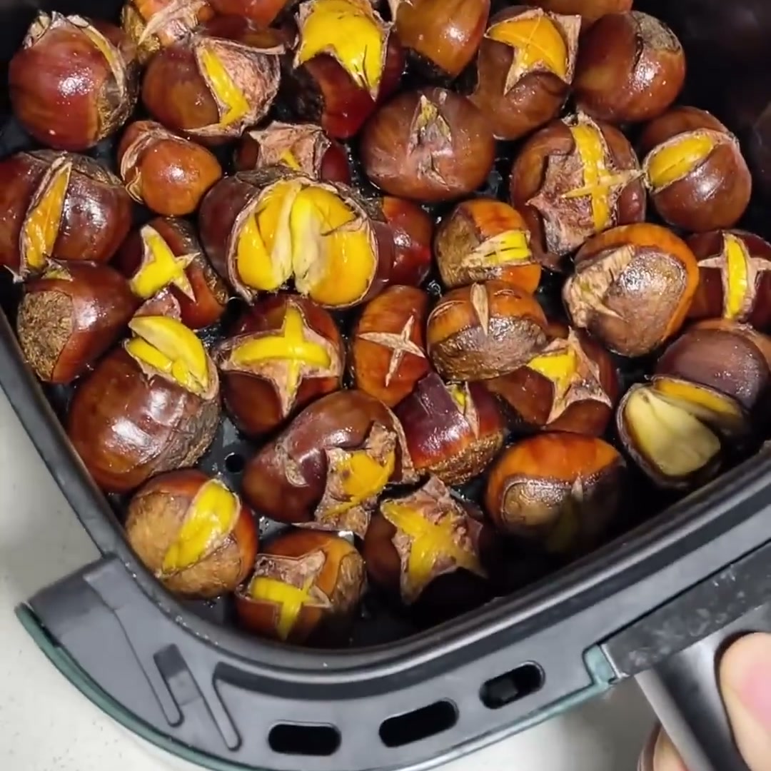 Roasted chestnuts with split shells in an air fryer basket