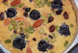 Baked oatmeal cake with blueberries, almonds, pumpkin seeds and raisins in a foil tray