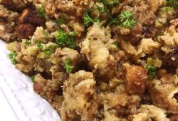 Sausage and herb stuffing with sage sausage and parsley on a white platter